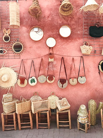 Aesthetic display of handmade wicker and straw accessories against a textured pink wall. HD phone wallpaper