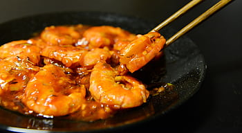 Close-up of spicy prawns in sauce with chopsticks on a dark plate HD wallpaper