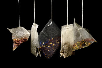 Assorted hanging tea bags on black backdrop showcasing different herbal blends. HD wallpaper