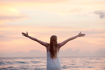 A woman enjoying a serene sunset on Unawatuna Beach, Sri Lanka, depicting peace and dom. HD wallpaper