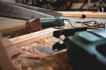 Close-up of various woodworking tools in a workshop, featuring wood shavings and equipment. HD wallpaper