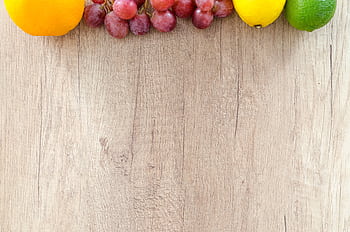 Fresh oranges, grapes, lemon, and lime arranged on a wooden chopping board, offering vibrant colors. HD wallpaper