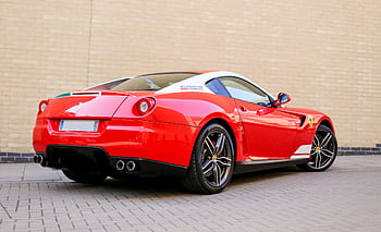 Rear view of a luxurious red sports car parked on a brick pavement showcasing its sleek design. HD wallpaper