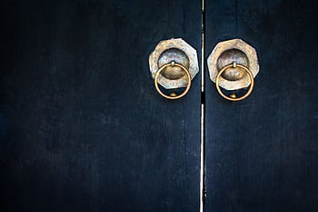 Close-up of vintage wooden doors featuring brass circular handles, showcasing traditional design elements. HD wallpaper