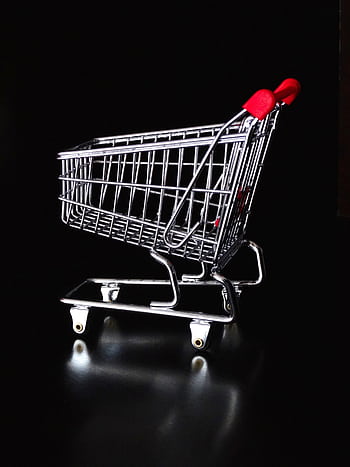 A shiny miniature shopping cart with red handles on a black reflective surface. HD phone wallpaper