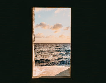 Tranquil ocean view framed by an open doorway at sunset, showcasing nature's simplicity. HD wallpaper