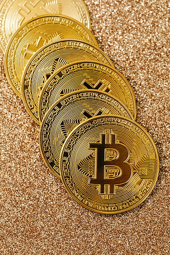 Golden Bitcoin cryptocurrency coins stacked on a glittering surface representing digital wealth and blockchain. HD phone wallpaper