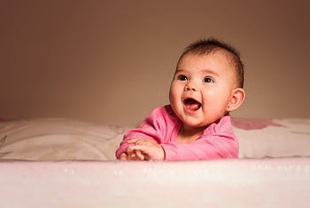 Charming portrait of a smiling baby girl in pink indoors, exuding happiness and innocence. HD wallpaper