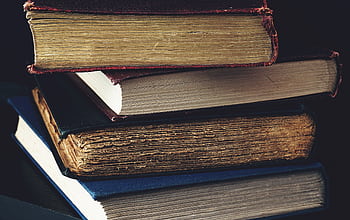 Close-up of a stack of vintage books with worn bindings, showcasing aged paper and textures. HD wallpaper