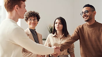 Four colleagues in an office handshake demonstrating teamwork and cooperation. HD wallpaper