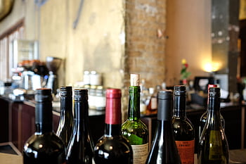A selection of wine bottles with corks on a restaurant bar counter, ideal for gastronomy themes. HD wallpaper