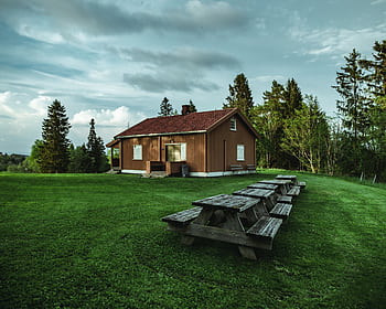 A rustic house in Norway's peaceful countryside, surrounded by lush greenery and wooden furniture. HD wallpaper