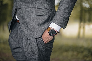Close-up of a man in a tailored suit wearing an elegant wristwatch outdoors, exuding fashion and sophistication. HD wallpaper