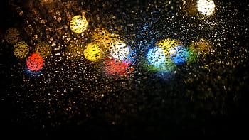 Abstract of colorful raindrops on glass with bokeh lights at night, creating a vibrant texture. HD wallpaper