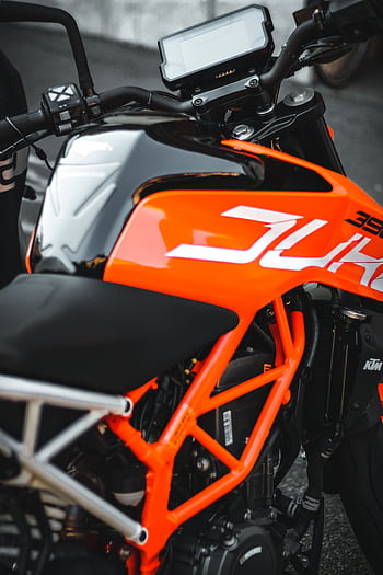 Close-up of a modern orange motorcycle showcasing its sleek design and vibrant color. HD phone wallpaper