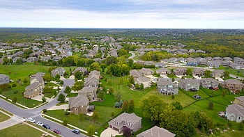 Aerial view of a suburban neighborhood with houses, roads, and lush greenery. HD wallpaper
