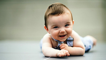 Smiley Cute Baby Is Lying Down On Floor Wearing Light Blue Dress In Blur Background Cute HD wallpaper