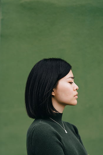 Side profile portrait of a young woman with dark hair against a green background. HD phone wallpaper