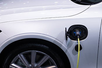 A white electric car is plugged in for charging, close-up view of the charging port. HD wallpaper
