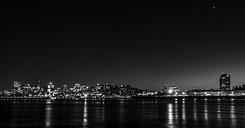 Stunning black and white panoramic view of Montreal's cityscape illuminated at night, reflecting on calm waters. HD wallpaper
