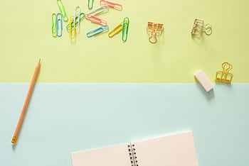 Top view of colorful stationery items, including a notebook, pencil, paperclips, and an eraser on pastel background. HD wallpaper