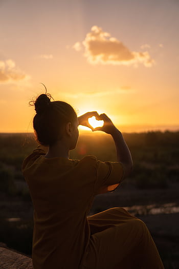 Silhouette of a person forming a heart with hands against a Morocco sunset. HD phone wallpaper