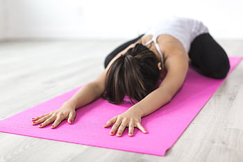 Adult woman practicing yoga in child's pose on pink mat indoors, focusing on relaxation and mindfulness. HD wallpaper
