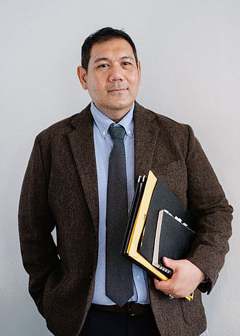 Confident Asian businessman holding folders with hand in pocket indoors. HD phone wallpaper