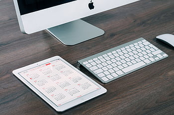 A sleek and modern office desk setup featuring an iMac, iPad with calendar, keyboard, and mouse. HD wallpaper