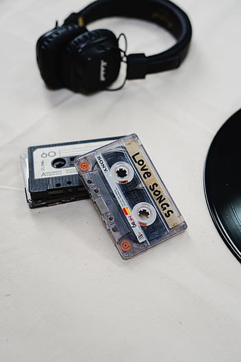 Flat lay of nostalgic cassette tapes labeled 'Love Songs' with black heads and vinyl record. HD phone wallpaper