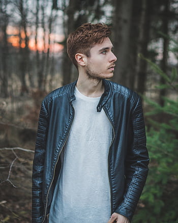Young man in a black leather jacket standing in a forest during twilight, styled fashion portrait. HD phone wallpaper