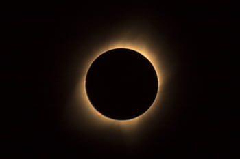 A captivating view of a solar eclipse highlighting the glowing corona in a dark sky. HD wallpaper