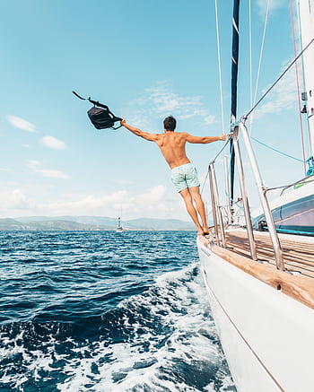 Man enjoying dom by jumping into the ocean from a sailboat in Greece. HD phone wallpaper