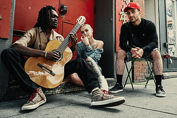 Diverse musicians perform on a city street, showcasing urban culture and friendship. HD wallpaper