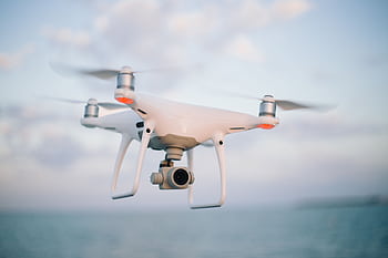 Aerial view of a modern drone flying above the ocean during the day. HD wallpaper