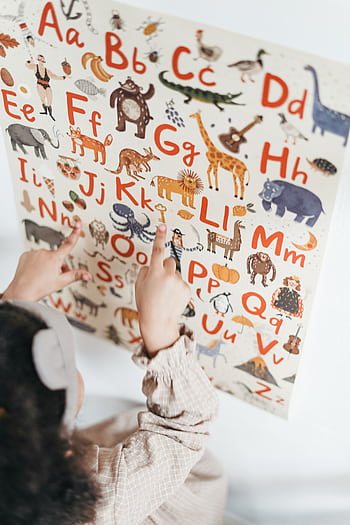 A child points at an educational alphabet poster with animals and letters. HD phone wallpaper