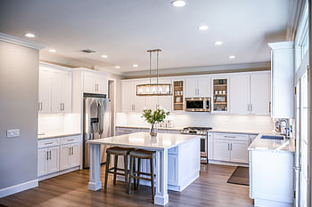 Elegant white kitchen featuring an island, modern appliances, and ample natural light. HD wallpaper