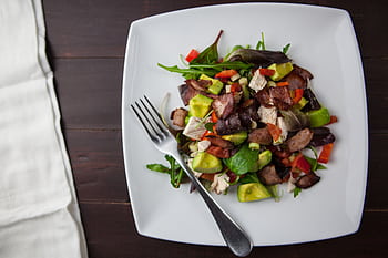 A fresh bacon, avocado, and mixed greens salad served on a square plate with a fork. HD wallpaper