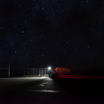 A quiet road scene with a bicycle under a vast starlit sky, emphasizing solitude and adventure. HD phone wallpaper