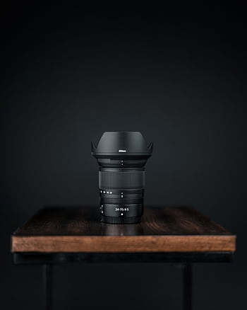 Close-up of a black camera lens on a wooden table against a dark background. HD phone wallpaper