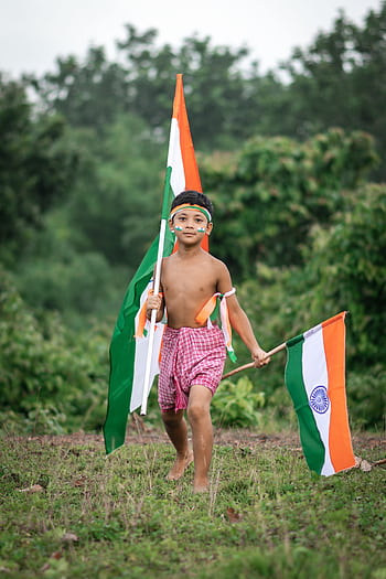 A young Indian boy joyfully waving the national flag outdoors, symbolizing Indian independence. HD phone wallpaper