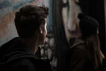 Young adults near urban street art. Moody and artistic shot with deep shadows. HD wallpaper