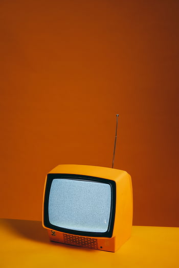Vintage yellow TV set with antenna against a vibrant orange backdrop creating a retro feel. HD phone wallpaper