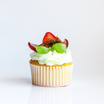 Close-up of a cupcake topped with strawberries, grapes, and chocolate curls, perfect for dessert lovers. HD phone wallpaper