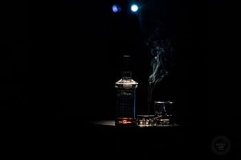 A dramatic whiskey bottle with smoke on a dark background, accented by soft lighting. HD wallpaper