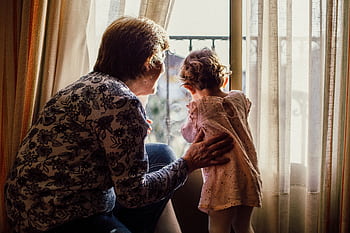 A loving moment between grandmother and grandchild near a window filled with sunlight. HD wallpaper