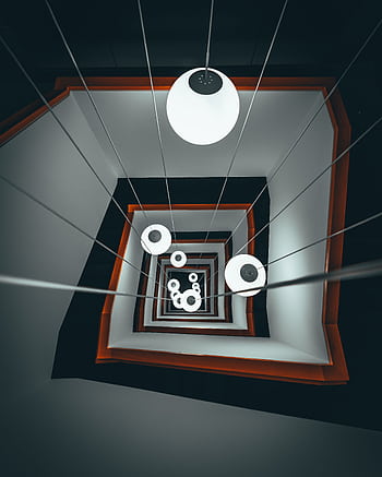 Dramatic view of a spiral staircase with modern lighting, creating a captivating pattern. HD phone wallpaper