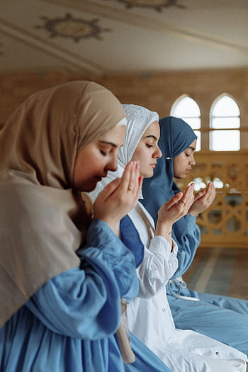 Three women in hijab engage in prayer inside a mosque, reflecting spirituality and faith. HD phone wallpaper