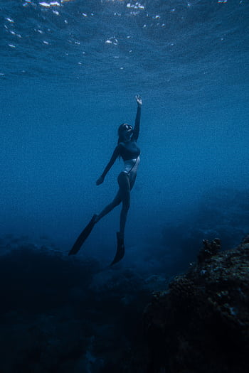 A captivating of a swimmer exploring the deep blue ocean underwater, embracing the serenity of marine life. HD phone wallpaper