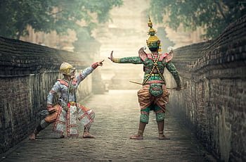 Two performers in vibrant traditional costumes performing a cultural dance outdoors. HD wallpaper